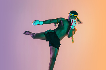 Image showing Muay thai. Young man exercising thai boxing on gradient background