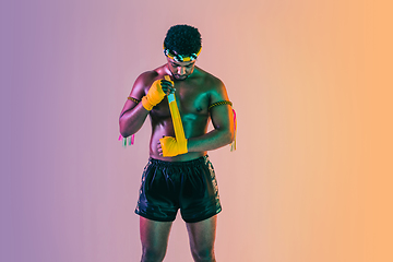 Image showing Muay thai. Young man exercising thai boxing on gradient background