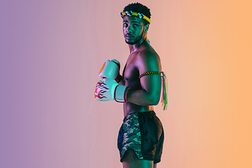 Image showing Muay thai. Young man exercising thai boxing on gradient background