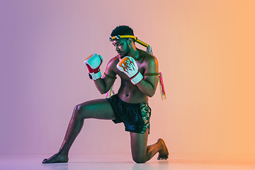 Image showing Muay thai. Young man exercising thai boxing on gradient background