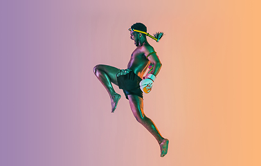 Image showing Muay thai. Young man exercising thai boxing on gradient background