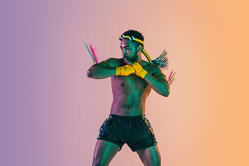 Image showing Muay thai. Young man exercising thai boxing on gradient background