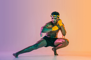 Image showing Muay thai. Young man exercising thai boxing on gradient background