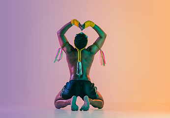 Image showing Muay thai. Young man exercising thai boxing on gradient background