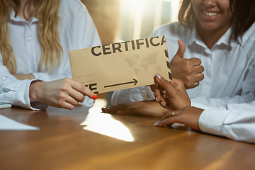 Image showing Close up of african-american and caucasian human\'s hands holding certificate or inviting card