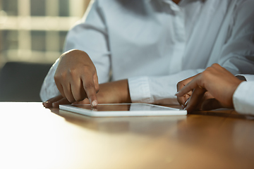 Image showing Close up of african-american human\'s hands using tablet on wooden table