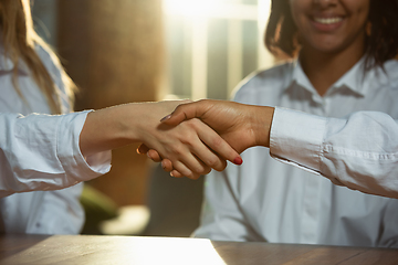 Image showing Close up of african-american and caucasian human\'s hands holding on wooden table