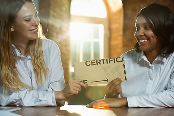 Image showing Close up of african-american and caucasian human\'s hands holding certificate or inviting card