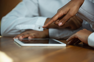 Image showing Close up of african-american human\'s hands using tablet on wooden table