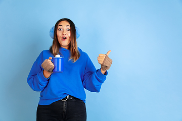 Image showing Caucasian woman\'s portrait isolated on blue studio background, winter theme