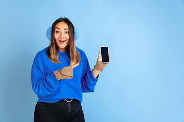 Image showing Caucasian woman\'s portrait isolated on blue studio background, winter theme