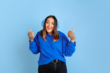 Image showing Caucasian woman\'s portrait isolated on blue studio background, winter theme