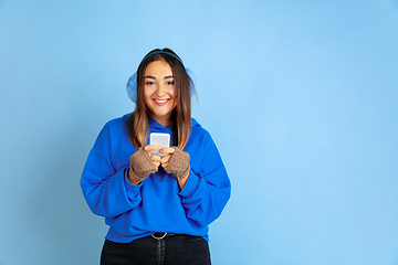 Image showing Caucasian woman\'s portrait isolated on blue studio background, winter theme