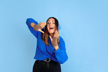 Image showing Caucasian woman\'s portrait isolated on blue studio background, winter theme