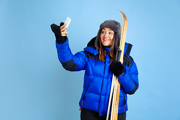 Image showing Caucasian woman\'s portrait isolated on blue studio background, winter theme