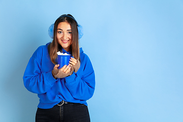 Image showing Caucasian woman\'s portrait isolated on blue studio background, winter theme