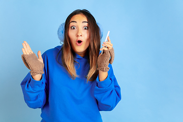 Image showing Caucasian woman\'s portrait isolated on blue studio background, winter theme