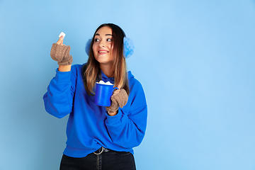 Image showing Caucasian woman\'s portrait isolated on blue studio background, winter theme