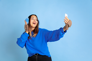 Image showing Caucasian woman\'s portrait isolated on blue studio background, winter theme