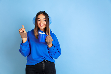 Image showing Caucasian woman\'s portrait isolated on blue studio background, winter theme