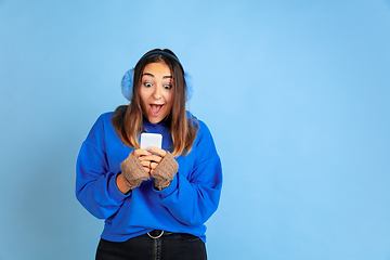 Image showing Caucasian woman\'s portrait isolated on blue studio background, winter theme