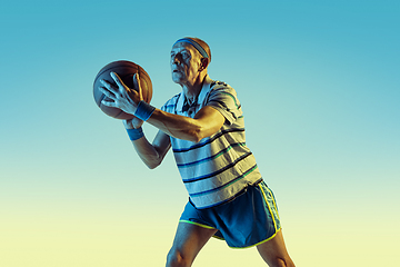 Image showing Senior man playing basketball in sportwear on gradient background and neon light