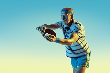 Image showing Senior man playing table tennis in sportwear on gradient background and neon light