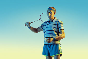 Image showing Senior man playing volleyball in sportwear on gradient background and neon light