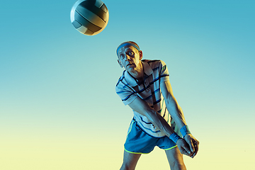 Image showing Senior man playing volleyball in sportwear on gradient background and neon light