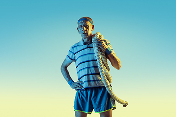 Image showing Senior man training with ropes in sportwear on gradient background and neon light