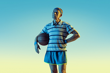 Image showing Senior man playing basketball in sportwear on gradient background and neon light