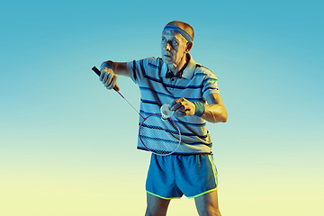 Image showing Senior man playing volleyball in sportwear on gradient background and neon light