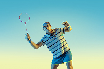 Image showing Senior man playing volleyball in sportwear on gradient background and neon light