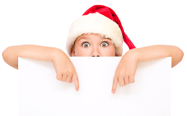 Image showing Little girl in santa hat is holding blank board