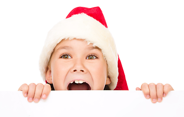 Image showing Little girl in santa hat is holding blank board