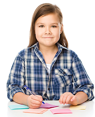 Image showing Girl is writing on color stickers using pen