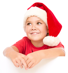 Image showing Little girl in santa hat is holding blank board