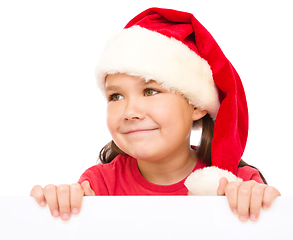 Image showing Little girl in santa hat is holding blank board