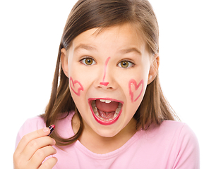 Image showing Little girl is applying lipstick on her cheek