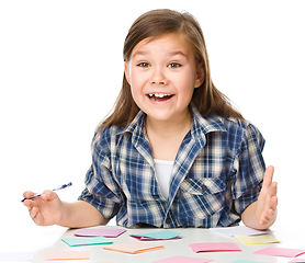 Image showing Girl is writing on color stickers using pen