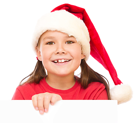 Image showing Little girl in santa hat is holding blank board