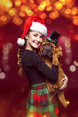 Image showing Pretty girl in christmas hat with shar pei puppy