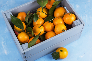 Image showing Fresh tangerines in box with leaves