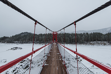 Image showing Suspension hanging bridge above winter frozen river