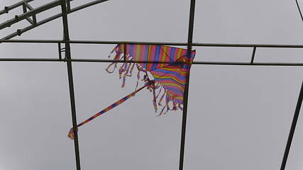 Image showing Kite is stuck in the metal structure against the sky.