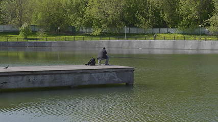 Image showing Fisherman catches fish in the lake with a fishing rod.