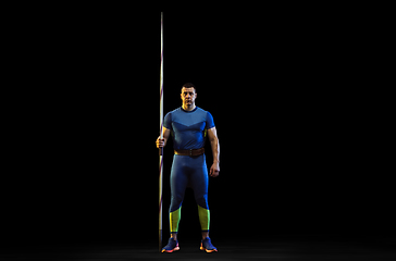 Image showing Male athlete practicing in throwing javelin isolated on black studio background in neon light