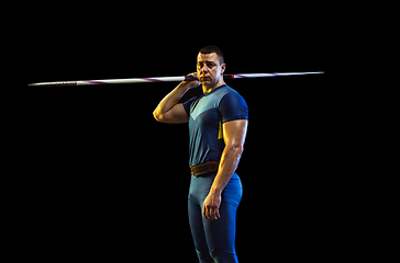 Image showing Male athlete practicing in throwing javelin isolated on black studio background in neon light