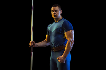 Image showing Male athlete practicing in throwing javelin isolated on black studio background in neon light