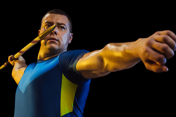Image showing Male athlete practicing in throwing javelin isolated on black studio background in neon light